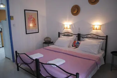 a bedroom with a large bed with two chairs at Sunset Rooms in Agia Marina Aegina