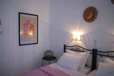 a bedroom with a bed and a picture on the wall at Sunset Rooms in Agia Marina Aegina