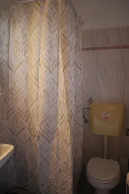 a bathroom with a toilet and a shower curtain at Sunset Rooms in Agia Marina Aegina