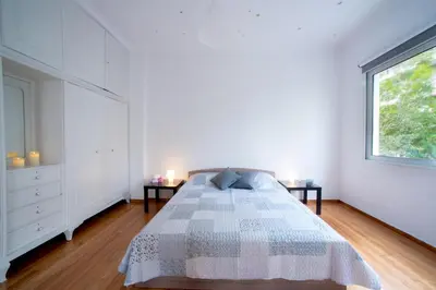 a white bedroom with a bed and two side tables at Central 5 Room Apartment in Athens