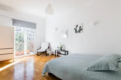 a white bedroom with a bed and a chair at Central 5 Room Apartment in Athens