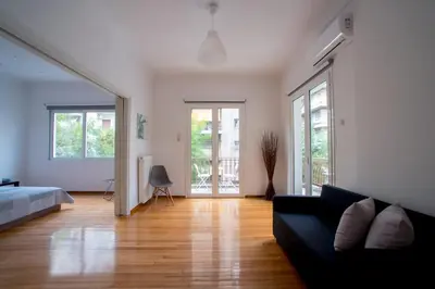 a living room with a black couch and wooden floors at Central 5 Room Apartment in Athens