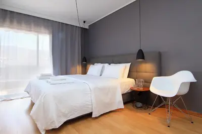 a bedroom with a white bed and a white chair at Central Apartment in Athens