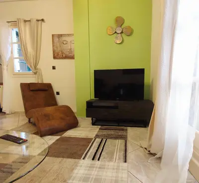 a living room with a flat screen tv and a chair at Elia Apartments in Athens