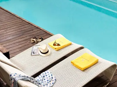a table with a hat and sunglasses next to a swimming pool at Acropolis Hill Hotel in Athens