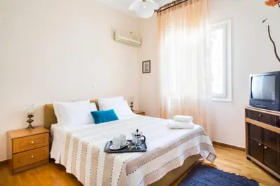 a white bedroom with a bed and a tv at Large 3 bedroom Apt with Terrace in Athens