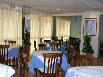 a dining room with tables and chairs with blue and white table cloth at Apollo Hotel in Athens