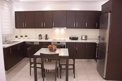 a kitchen with black cabinets and a table with chairs at Keratea Luxury Villa -Athens Airport in Keratea