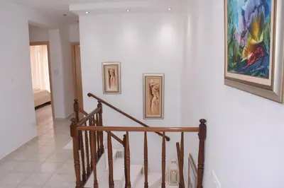 a staircase with three paintings on a white wall at Keratea Luxury Villa -Athens Airport in Keratea