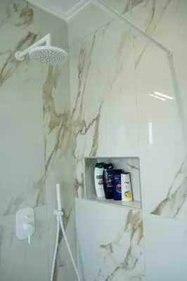 a bathroom with white marble walls and a shower at Keratea Luxury Villa -Athens Airport in Keratea