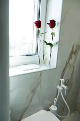 two roses in a vase on a window sill in a bathroom at Keratea Luxury Villa -Athens Airport in Keratea