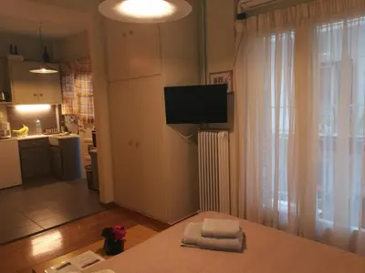 a living room with a tv on the wall and a kitchen at Koukaki ideal studio for 2 in Athens