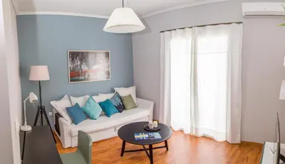 a living room with a white couch and blue pillows at Gazi Discrit Next To Subway in Athens