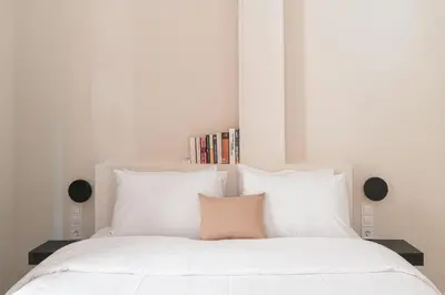 a white bed with white pillows and a pink pillow at Circle Inn in Athens
