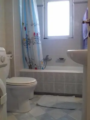 a bathroom with a toilet and a tub and a window at Blue Sky appartment in Pallíni