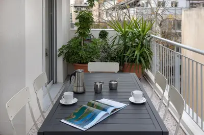 a black table on a balcony with coffee cups and a newspaper at Leonidas Loft in the heart of Athens by GHH in Athens