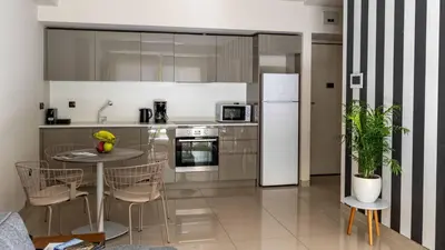 a kitchen with a table and a white refrigerator at Athens Mosaico Suites & Apartments in Athens