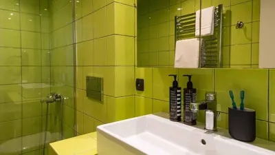 a green tiled bathroom with a sink and a shower at Athens Mosaico Suites & Apartments in Athens