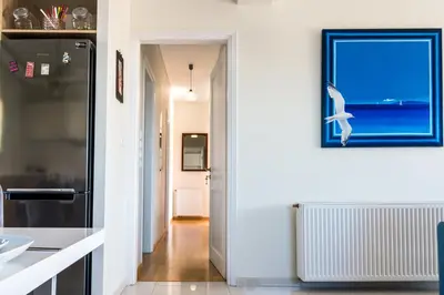 a kitchen with white walls and a blue picture on the wall at Leo - Unique Glyfada Apartment in Athens