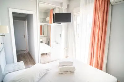a bedroom with a white bed and a mirror at Eva Hotel Piraeus in Piraeus