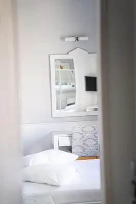 a white bedroom with a bed and a mirror at Eva Hotel Piraeus in Piraeus