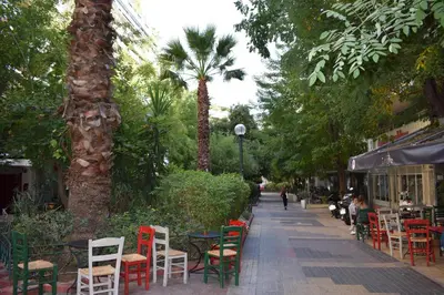a sidewalk with tables and chairs and palm trees at Absolute Athens II in Athens