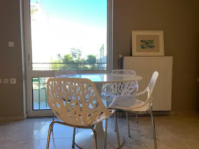 a dining room with a table and chairs and a window at Sepolia Apartment in Athens