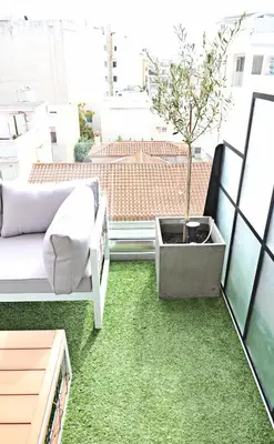 a small tree on a balcony with green carpet at The Athenians Modern Apartments in Athens