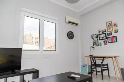 a living room with a tv and a table and a window at Gazi Area close to Subway in Athens