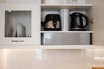 a white cupboard with dishes and appliances in it at Super Stylish Apartments in Syntagma Square! in Athens