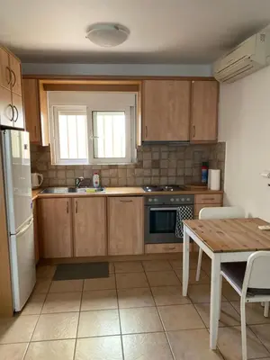 a kitchen with wooden cabinets and a table and a refrigerator at The Little Studio Koukaki - Acropolis in Athens