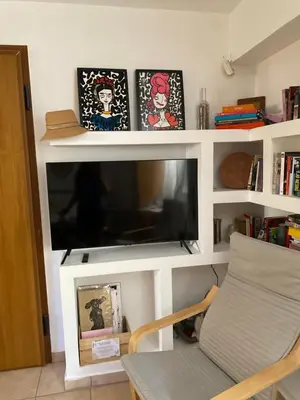 a living room with a tv in a white shelf at The Little Studio Koukaki - Acropolis in Athens