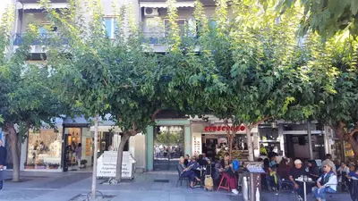a group of people sitting at tables in front of a store at Acropolis Heart in Athens