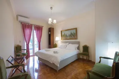 a bedroom with a white bed and two chairs at Keramikos Cozy Apartment by YHA in Athens