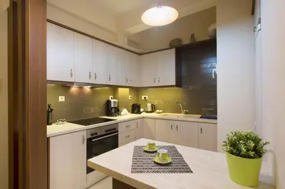 a kitchen with white cabinets and a table with cups on it at Keramikos Cozy Apartment by YHA in Athens