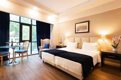 a hotel room with a bed and a table and chairs at Best Western Plus Embassy Hotel in Athens