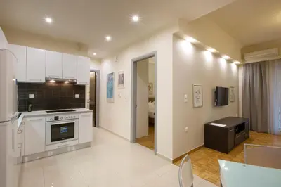 a kitchen with white cabinets and a stove top oven at Apartment at Koukaki, 150m from the metro by YHA in Athens