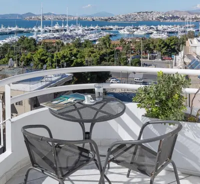 a table and chairs on a balcony with a view of a harbor at Nice Sea View Elegant Apartment in Athens