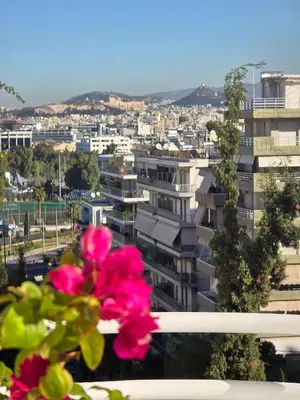 a pink flower on a window sill with a city at Nice Sea View Elegant Apartment in Athens