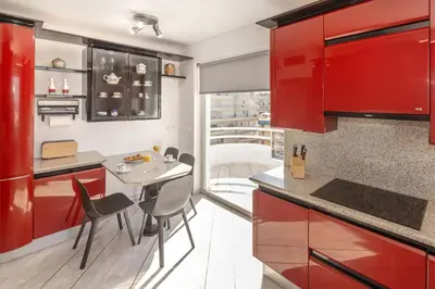a kitchen with red cabinets and a table with chairs at Nice Sea View Elegant Apartment in Athens