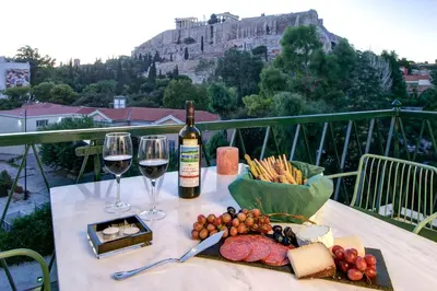 a table with two glasses of wine and a plate of food at Frixos Acropolis Luxury Apartment in Athens
