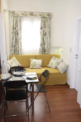 a living room with a yellow couch and a table at Be My Guest Apartment in Athens