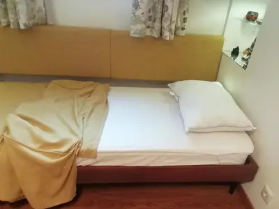 a bed with white sheets and a wooden headboard at Be My Guest Apartment in Athens