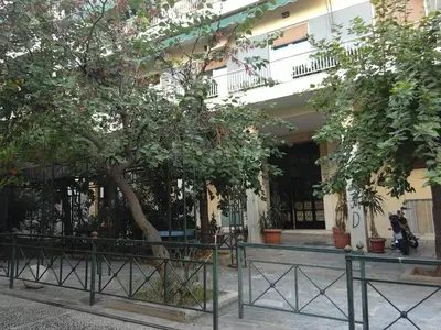 a tree in front of a building with a fence at Be My Guest Apartment in Athens