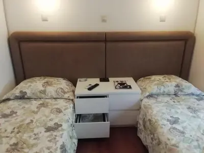 a room with two beds and a nightstand between them at Be My Guest Apartment in Athens