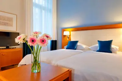 a vase of flowers on a table in a bedroom at Hapimag Apartments Athens in Athens