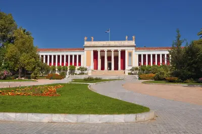 a building with red and white columns in a park at Hapimag Apartments Athens in Athens