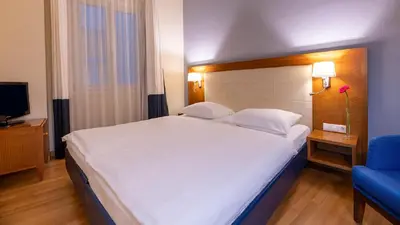 a bedroom with a large white bed and a blue chair at Hapimag Apartments Athens in Athens
