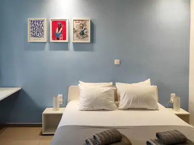 a bedroom with a white bed with three pictures on the wall at KYMA Apartments - Athens Acropolis 5 in Athens