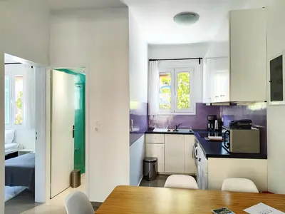 a kitchen with white cabinets and a table and chairs at KYMA Apartments - Athens Acropolis 5 in Athens